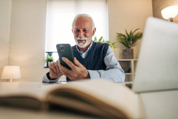 istock Senior man using smartphone and laptop at home office 2201052053