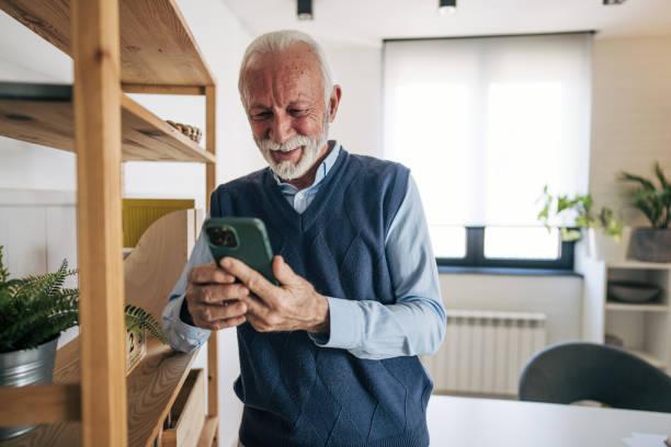 istock Senior man using smartphone and smiling at home 2201052057