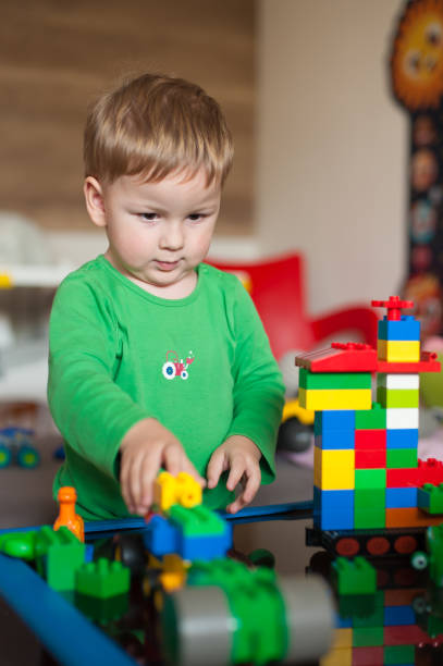istock Young child engages in creative play with colorful building blocks in a bright indoor setting 2201054007