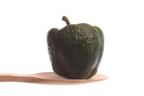Bell pepper simply offered on a wooden spoon isolated on a white background