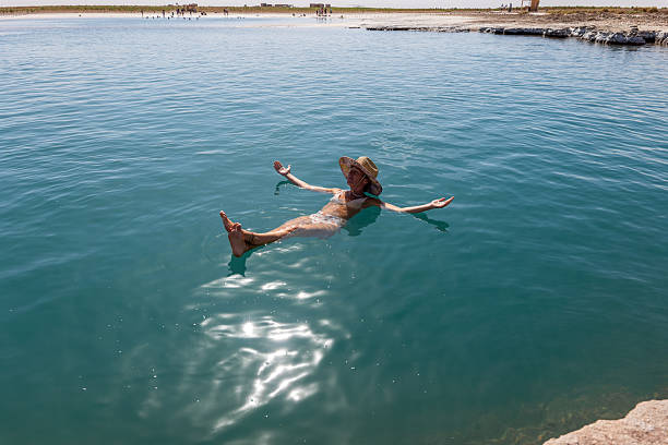 Woman enjoying a peaceful float in a clear lake, arms outstretched. Serene outdoor moment in nature.