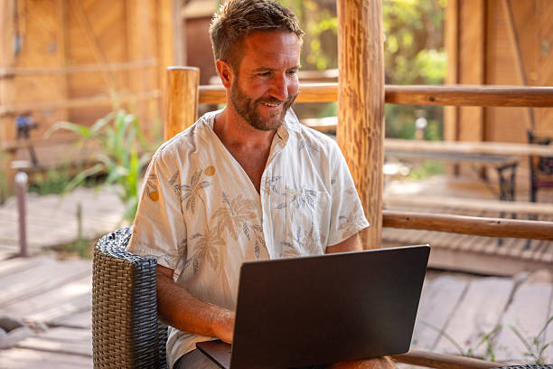 istock Man Relaxing in Tropical Outdoor Workspace with Laptop 2201056349