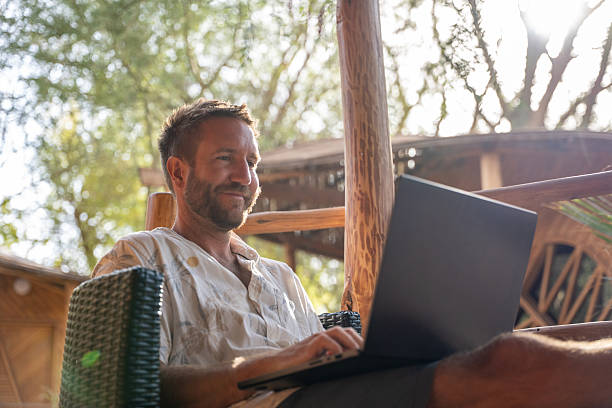 istock Man Relaxing in Tropical Outdoor Workspace with Laptop 2201056379