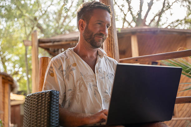 istock Man Relaxing in Tropical Outdoor Workspace with Laptop 2201056391