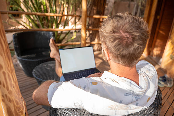 istock Relaxed man working on laptop in outdoor tropical setting 2201056443