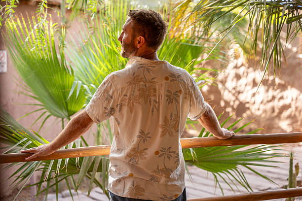 istock Man Relaxing on Tropical Patio Overlooking Lush Garden 2201056469