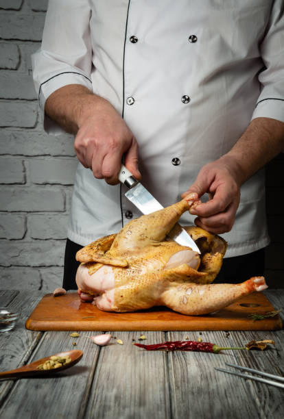 istock A skilled chef skillfully slices a marinated chicken on a wooden cutting board. The rustic kitchen, adorned with brick walls and culinary tools, creates a warm and inviting atmosphere for cooking 2201058812