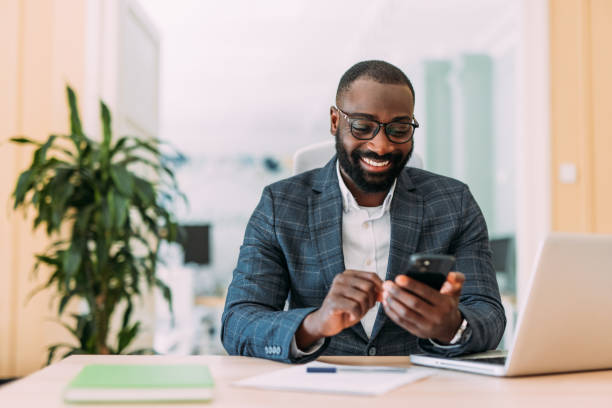 istock Businessman using laptop and texting on cellphone in the office. 2201058922
