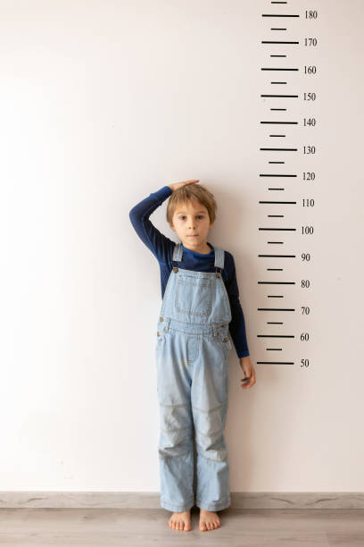 istock Little child, boy, measuring height against wall in room 2201065803