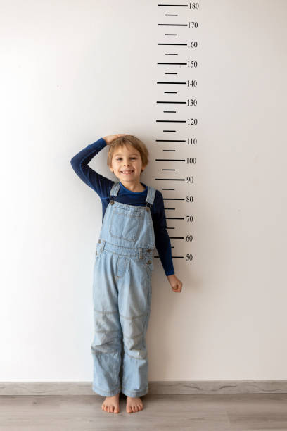 istock Little child, boy, measuring height against wall in room 2201065820