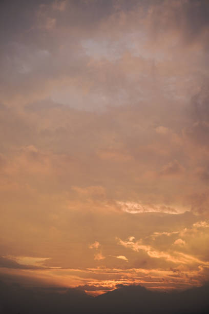 Warm, inviting sunset sky with soft orange and pink hues. Delicate clouds stretch across the frame, offering a peaceful and calming scene.