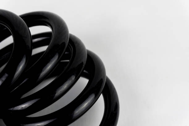 Close-up shot of a black coiled cable on a white background, showcasing its texture and smooth surface.
