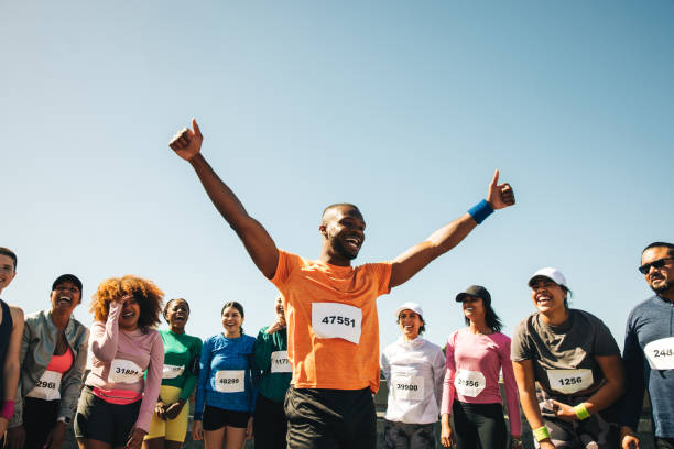 istock Runner celebrating victory with crowd at marathon finish line 2201066717