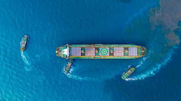 istock Aerial top view tugboat pushing empty container cargo ship to terminal commercial port for shipment. 2201066740