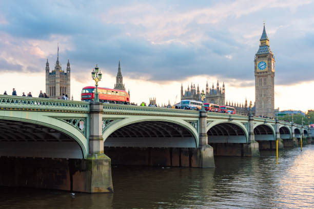 Double-decker buses on Westminster bridge and Big Ben tower at sunset, London, UK