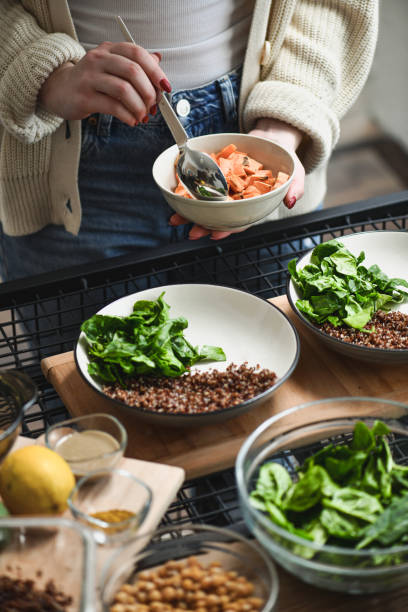 istock Female Adding Sweet Potato Slices to Homemade Nutritious Lunch Bowls 2201068348