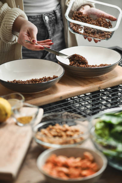 istock Female Making Buddha Bowls Adding Cooked Quinoa to Plates 2201069454