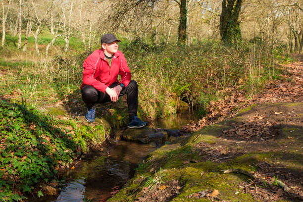 istock Hiker resting near a stream in the forest 2201076484