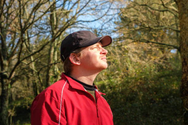 Portrait of a latin adult man breathing fresh air in the park by a lake on a sunny day.