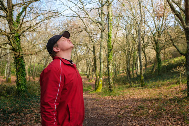 Young man enjoying fresh air in a peaceful forest, promoting wellness and connection with nature