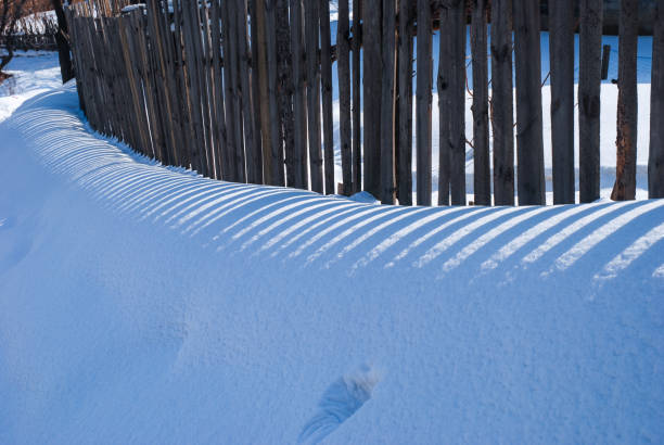 Shadows in the snow on the fence