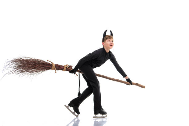 istock Young figure skater in a devil costume with a broomstick performing on the ice rink during Halloween 2201080933