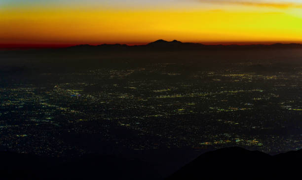 Captivating view of San Bernardino Valley at dusk from Rimforest, California, showcasing a blend of vibrant sunset colors and sparkling city lights.