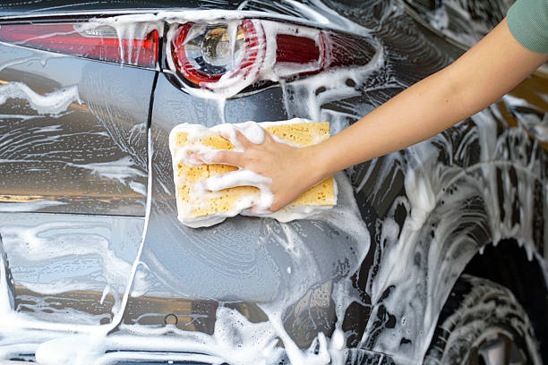 istock Hand holding sponge to scrub and clean dirt off the car 2201089142