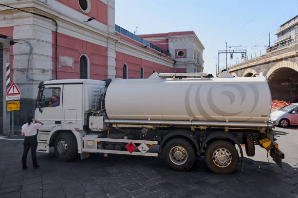 Catania, Italy - February 20, 2025: A white fuel tanker truck with safety hazard symbols during the transportation of hazardous materials in an urban environment