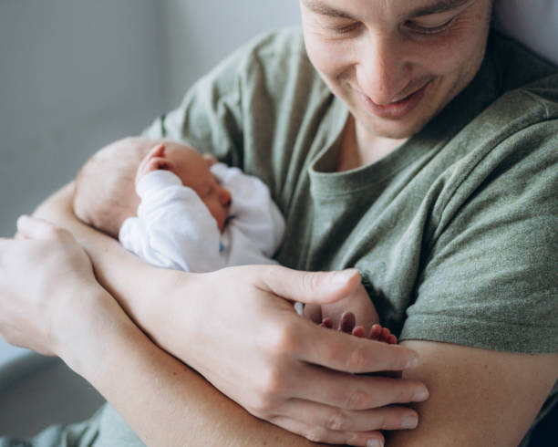 istock Father Smiling While Holding Newborn Baby in Arms 2201092005