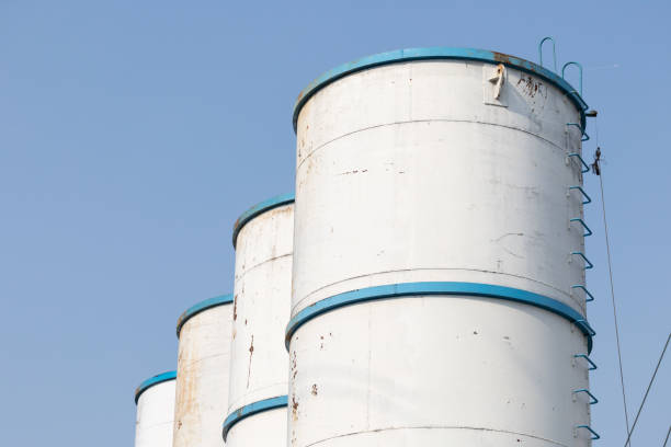 Three large white tanks with blue stripes. The tanks are empty and the sky is clear. The tanks are tall and the blue stripes are visible on the sides