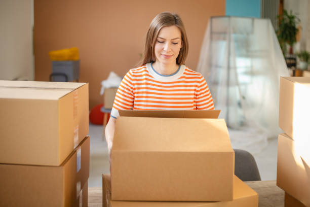 istock Young woman delighted while unpacking in her new apartment filled with boxes and hope for a bright future 2201092875