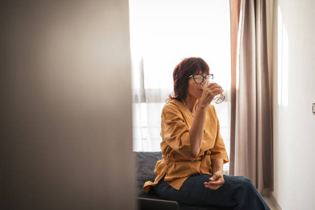 Woman drinking water while relaxing on a sunny day indoors