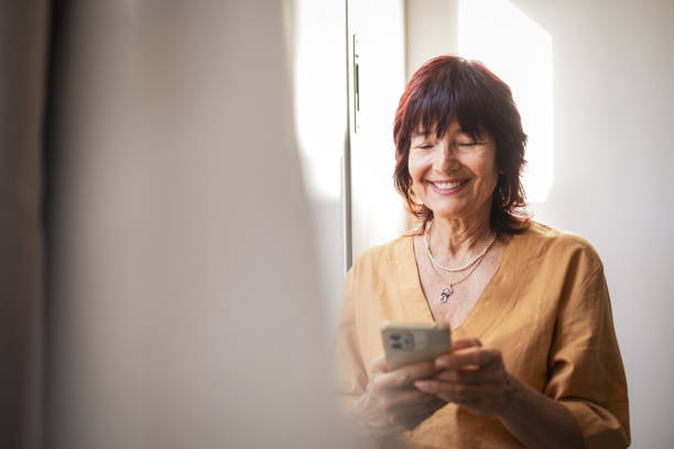 istock Smiling senior woman using a smartphone and enjoying her day indoors 2201098272