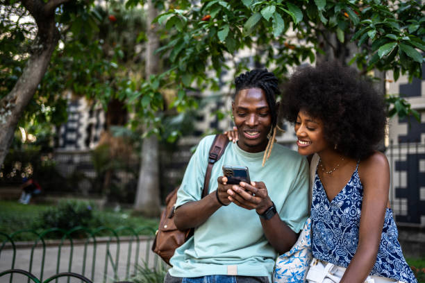 istock Young couple or friends talking and using mobile phone outdoors 2201099942