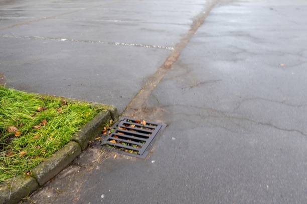 istock Storm drain collecting rainwater runoff in parking lot 2201100496