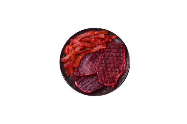 Dried beef slices, jerky, with cherry or plum flavor, salt and spices on a white background