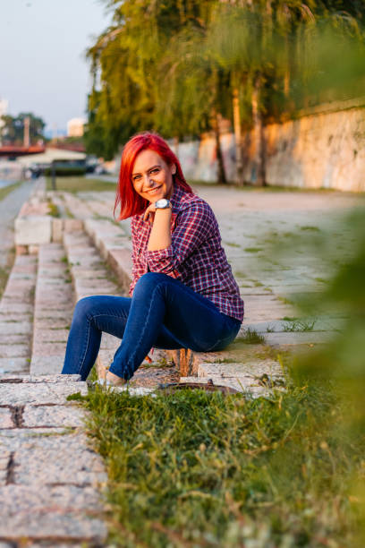 Portrait of a young redheaded woman sitting on the quayside.