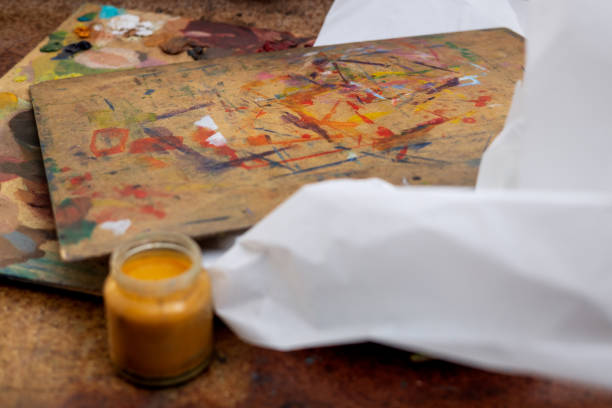 An old palette with oil paints in the artist's studio. Painted background created by a creative person. Close-up photo of a hobby.
