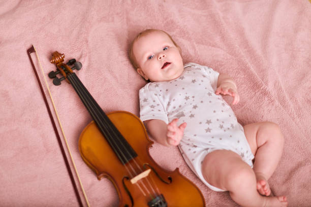 Baby girl with violin on soft pink blanket