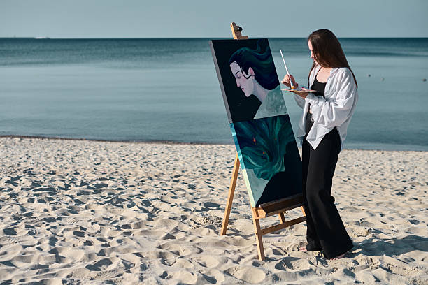 istock Female artist painting by seaside 2201103302