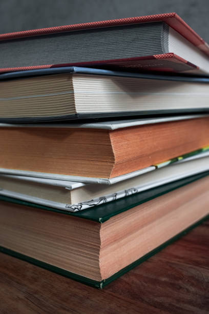 istock Stack of thick books on wooden table with pages close up 2201106079