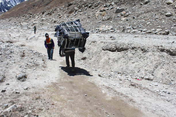 Gorakshep,Nepal - May 21 2017 -Nepali  Porters carry heavy loads on the Everest base camp trek trails towards Gorakshep,Nepal