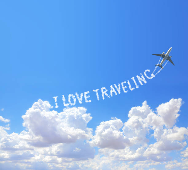 istock Blue sky with aircraft and Jet trailing smoke. Horizontal banner with airplane drawing a word I love traveling in sky. Topic of summer holiday, travel, trip abroad on vacation, cruises and tours 2201112732
