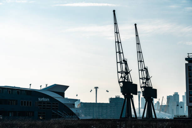 Two imposing cranes stand tall against the backdrop of london's skyline, capturing the essence of industrial history in royal victoria dock