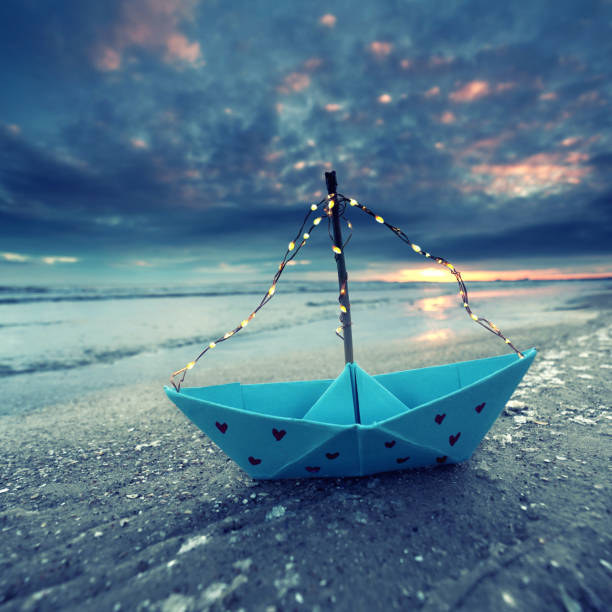 istock paper boat with red hearts and light string on the frozen winter beach 2201113530
