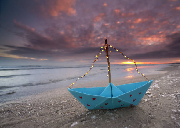 istock romantic lantern blue paper boat with red hearts and light string on the frozen winter beach 2201113533