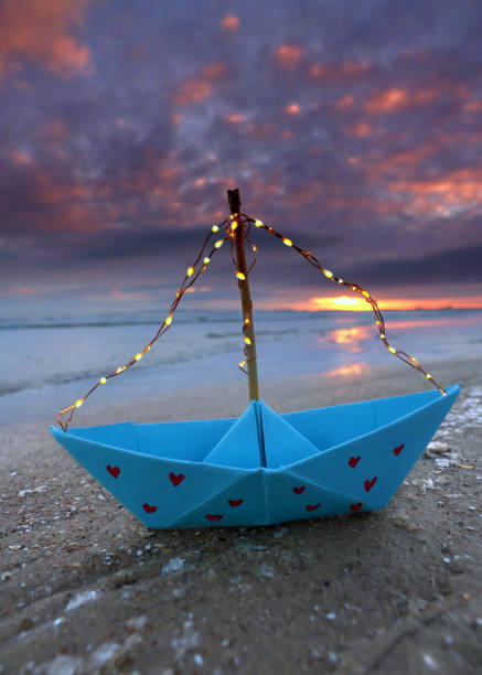 istock blue paper boat with red hearts and light string on the frozen winter beach 2201113670