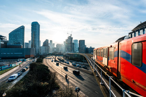 Commuter train passing over busy highway in london at sunset
