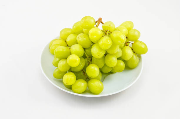 istock Cluster of white grapes on white round plate, white background. 2201116314